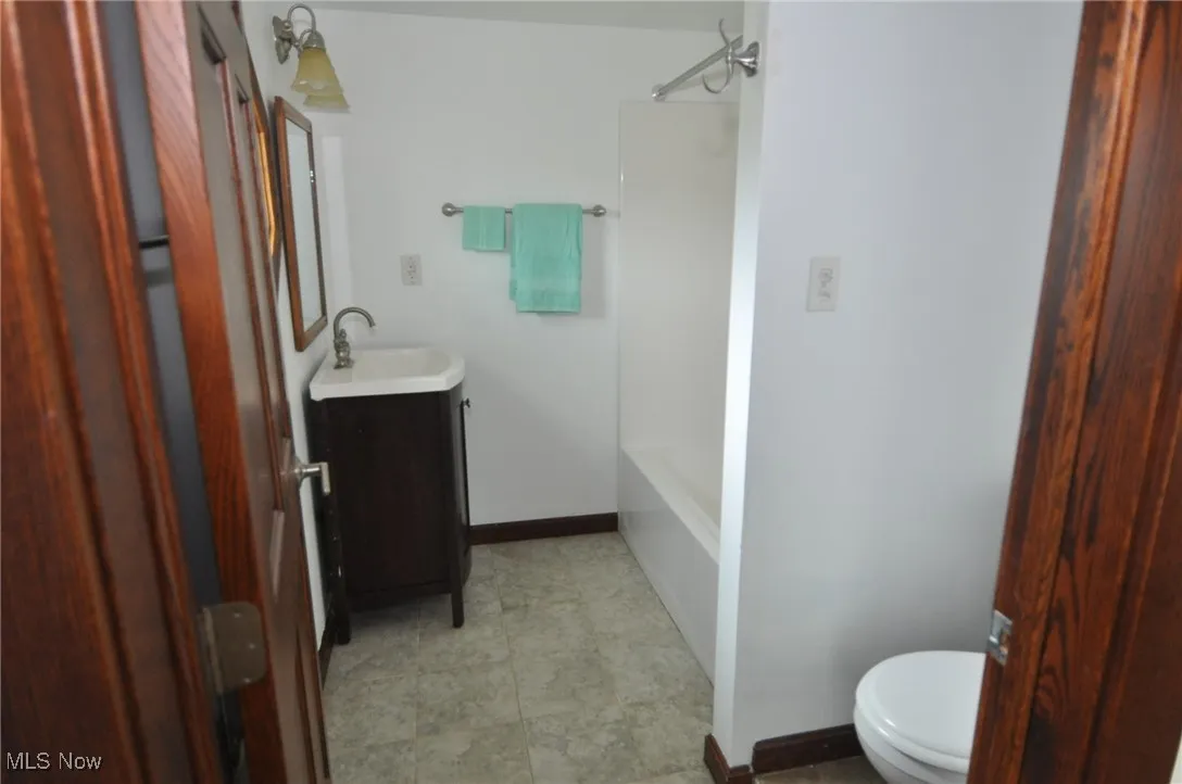 Second floor primary bathroom featuring toilet, vanity, baseboards, and tub / shower combination