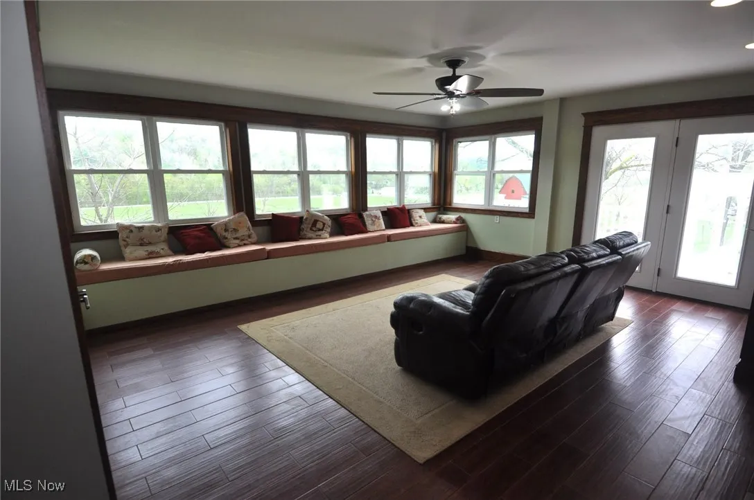 Living room with a ceiling fan and dark wood-style floors door to porch/patio