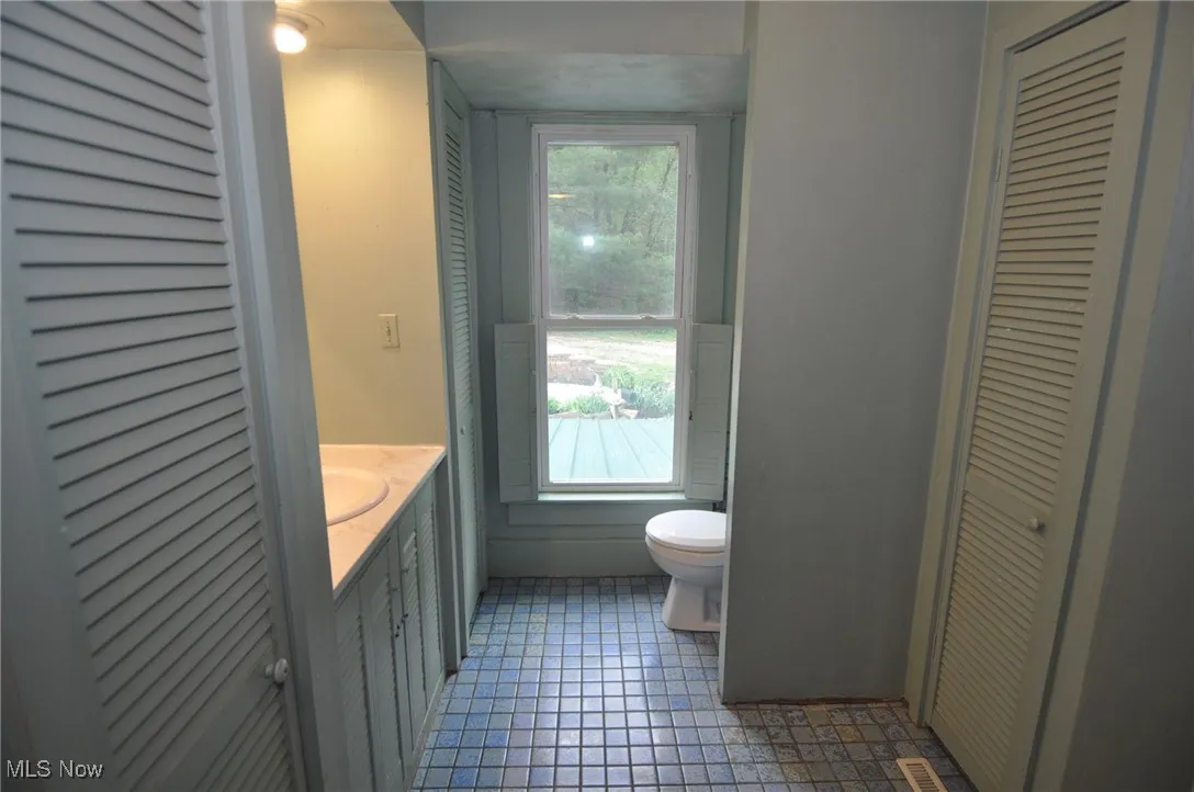 Second view of second floor bathroom featuring toilet, a closet, vanity, and tile patterned floors