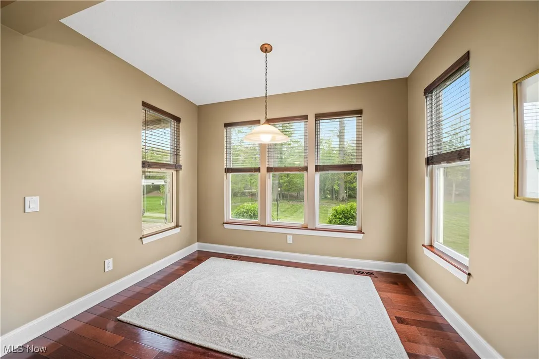 Unfurnished dining area featuring dark wood finished floors and baseboards