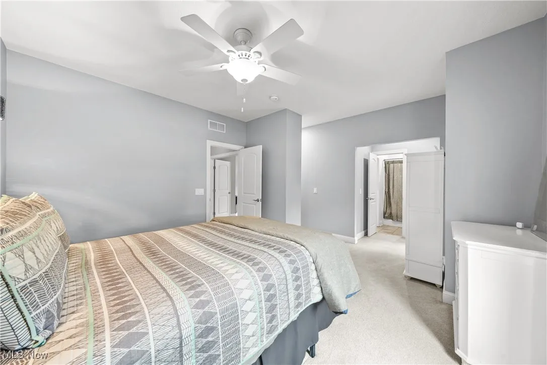Bedroom with light carpet, ceiling fan, and baseboards