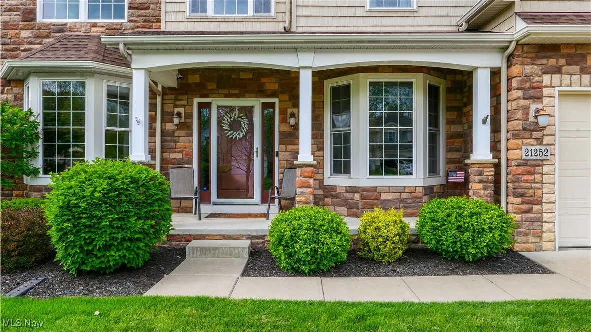 View of exterior entry with stone siding and a porch