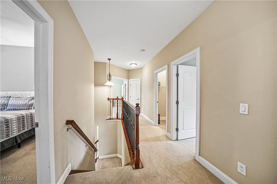 Hall with an upstairs landing, carpet floors, and baseboards
