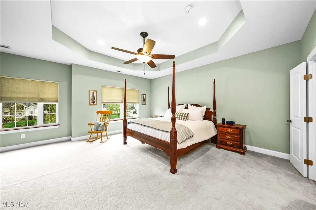 Carpeted bedroom with baseboards, a tray ceiling, a ceiling fan, and recessed lighting