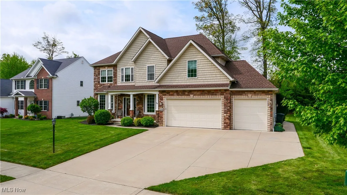 View of front of house with driveway, a front lawn, covered porch, an attached garage, and a shingled roof