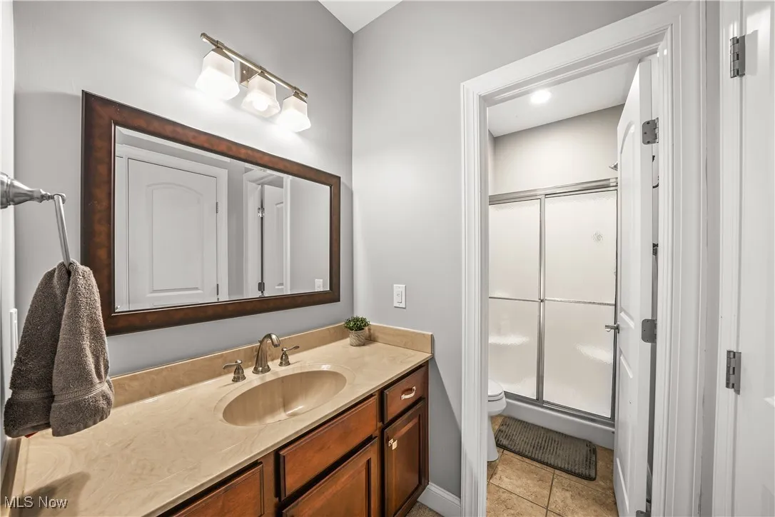 Full bathroom with a shower stall, vanity, toilet, and tile patterned floors