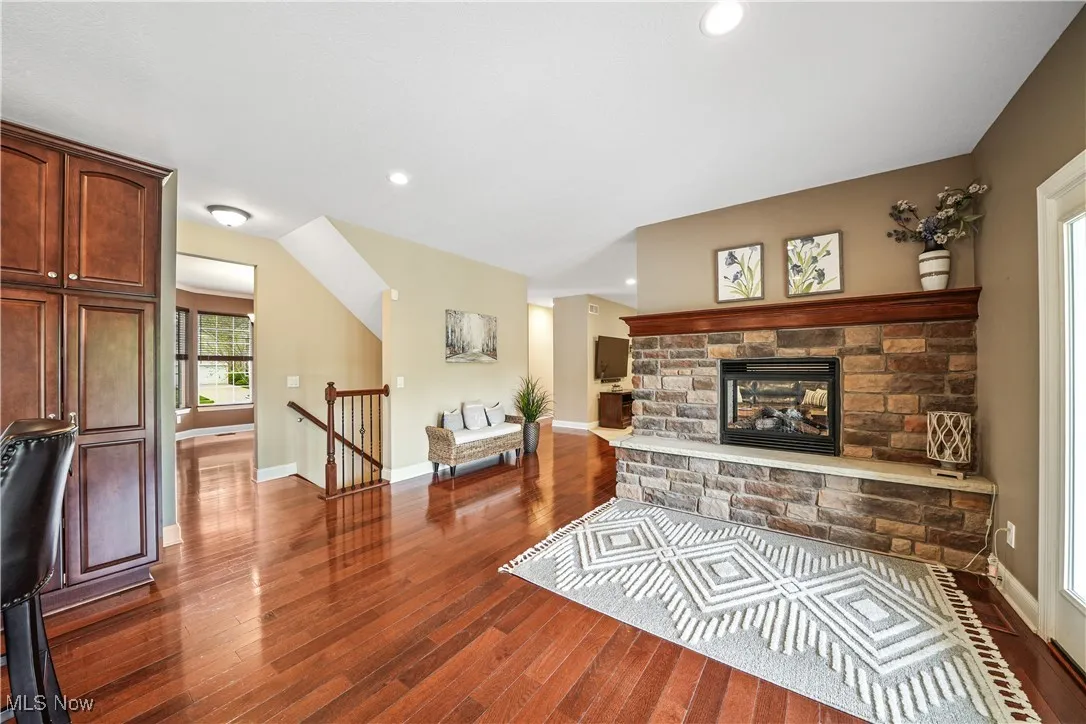 Living area with dark wood-style flooring, baseboards, recessed lighting, and a stone fireplace