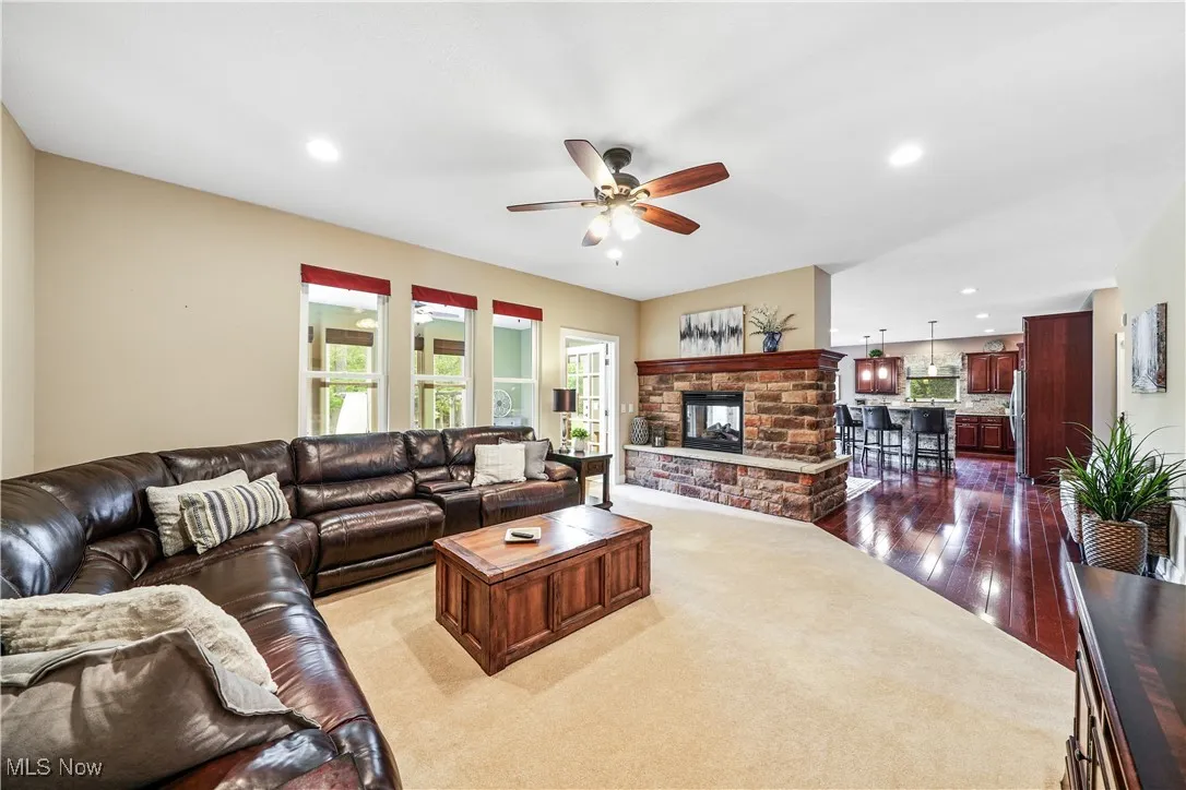 Living area with a ceiling fan, recessed lighting, dark wood-style floors, and a fireplace