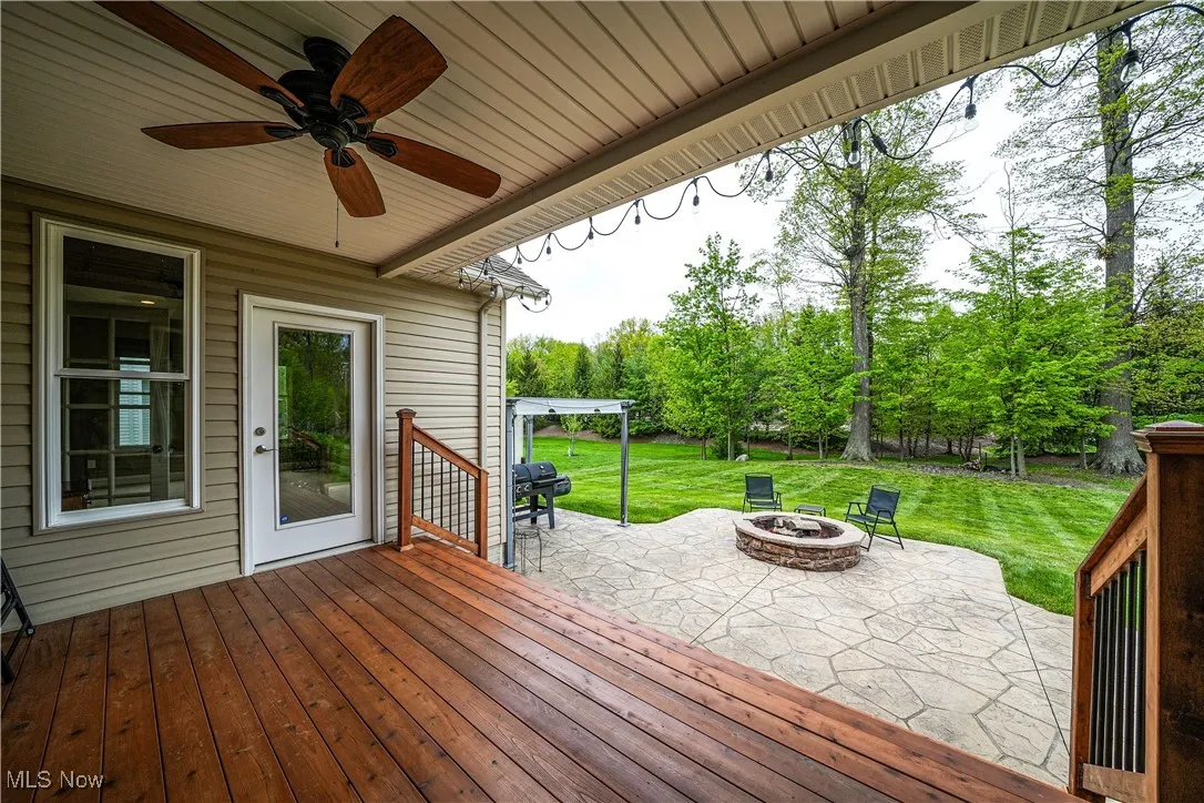 Deck with an outdoor fire pit, a patio, a yard, and a ceiling fan