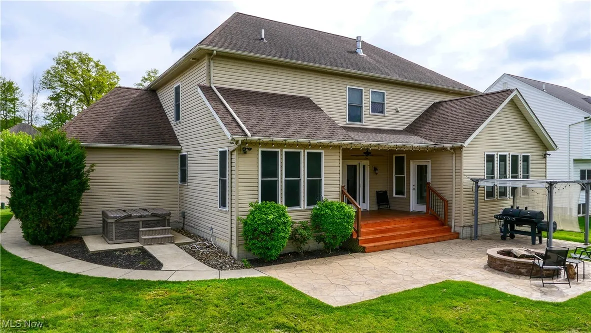 Back of house featuring an outdoor fire pit, a patio, a lawn, ceiling fan, and roof with shingles