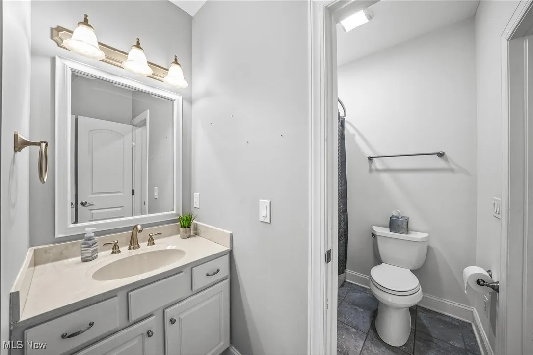 Full bathroom with toilet, vanity, tile patterned flooring, a shower with shower curtain, and baseboards