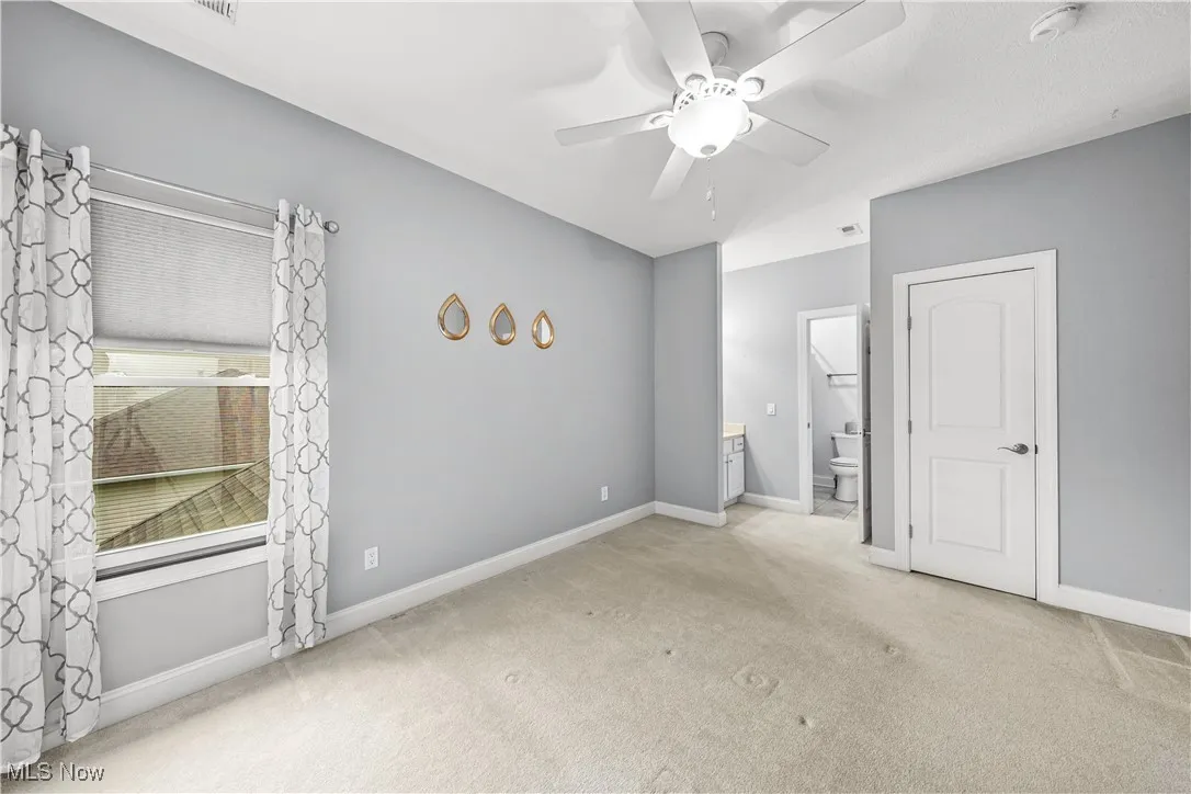 Unfurnished bedroom with carpet floors, connected bathroom, baseboards, and ceiling fan