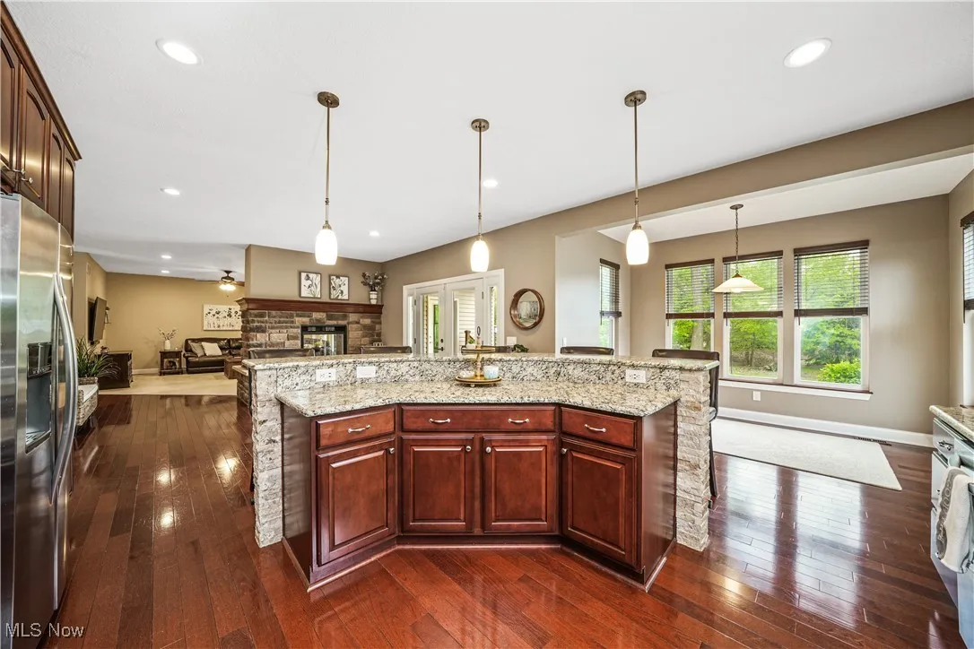 Kitchen with stainless steel fridge, open floor plan, dark wood-style flooring, pendant lighting, and recessed lighting