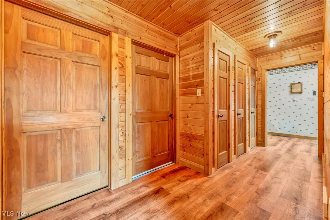 Hallway with wood ceiling, wood finished floors, and wooden walls