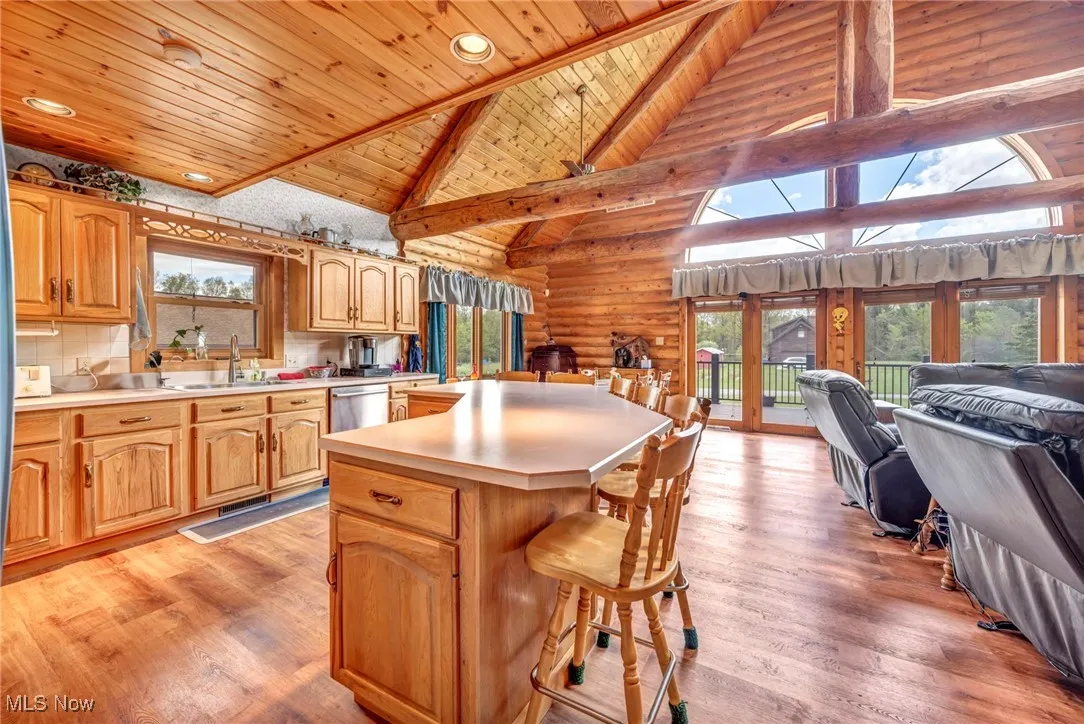 Kitchen featuring wooden ceiling, open floor plan, a sink, light countertops, and plenty of natural light