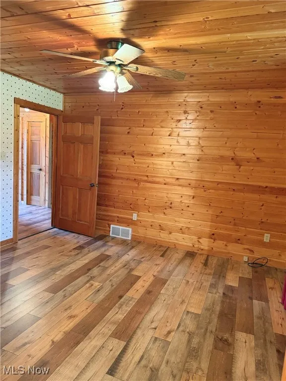 Unfurnished room with hardwood / wood-style flooring, a ceiling fan, wallpapered walls, and wooden ceiling
