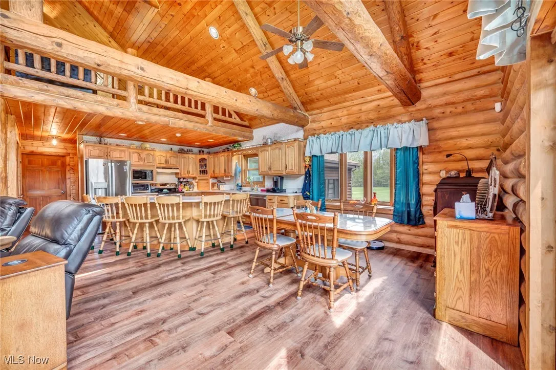 Dining area featuring wooden ceiling, ceiling fan, light wood finished floors, beam ceiling, and log walls