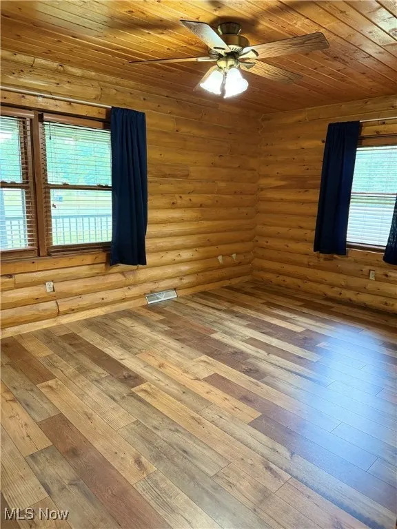 Empty room featuring a ceiling fan, hardwood / wood-style floors, plenty of natural light, and wooden ceiling