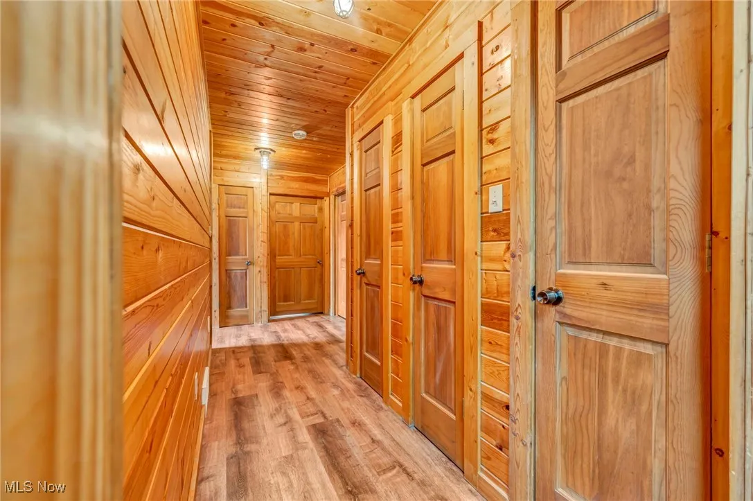 Corridor featuring wood walls, wooden ceiling, and light wood-style flooring