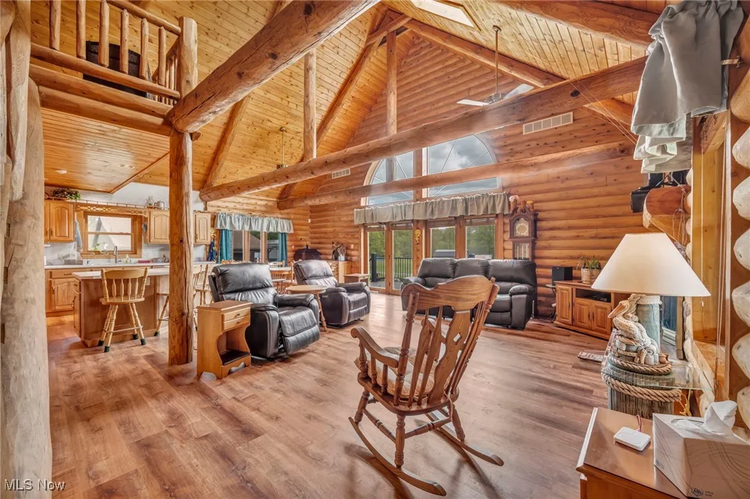 Living room featuring wooden ceiling, beamed ceiling, light wood-style floors, high vaulted ceiling, and log walls