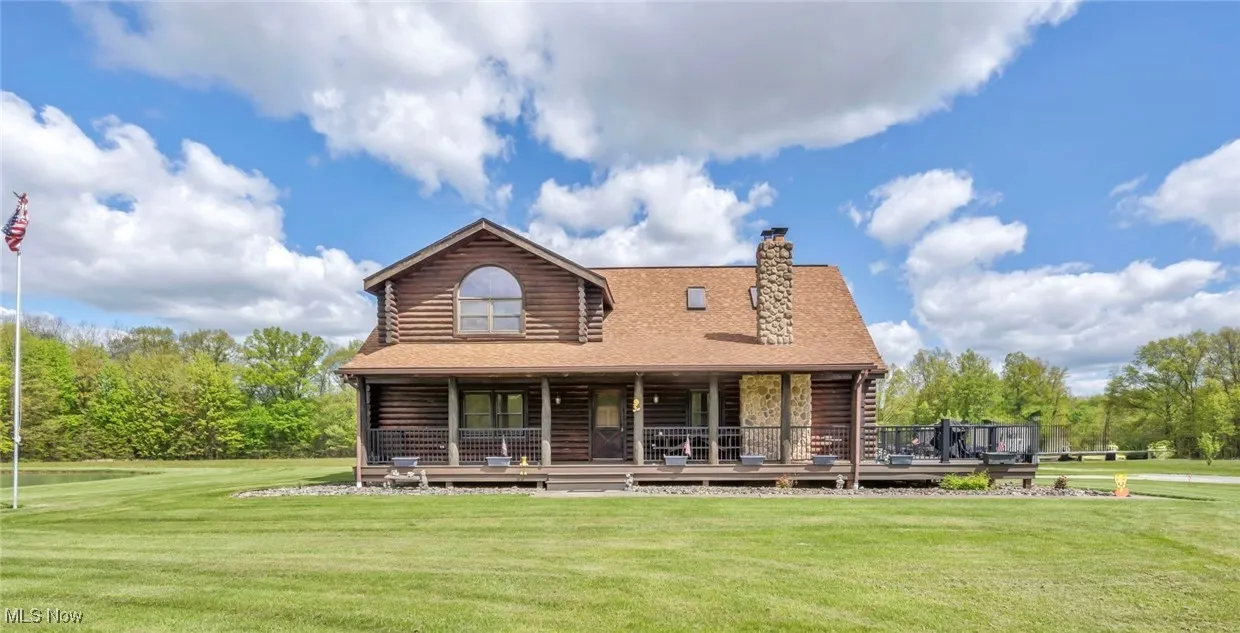 Front view of house with log siding, a lawn, and a chimney