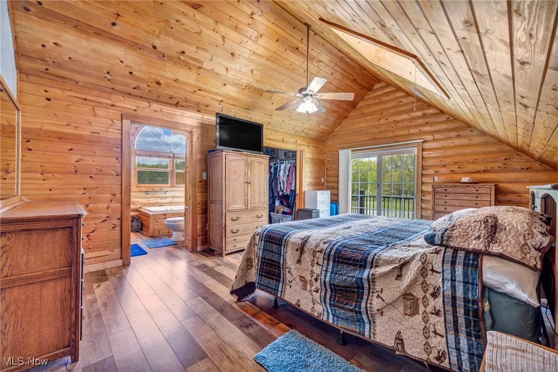 Bedroom with wooden ceiling, vaulted ceiling, ensuite bath, log walls, and a spacious closet
