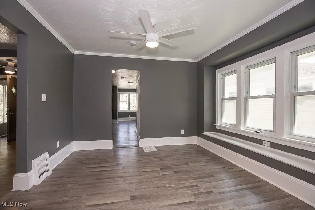 Dining room featuring baseboards, dark wood-type flooring, ceiling fan, and ornamental molding