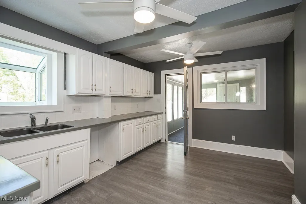 Kitchen with a sink, a ceiling fan, white cabinets, plenty of natural light, and a textured ceiling