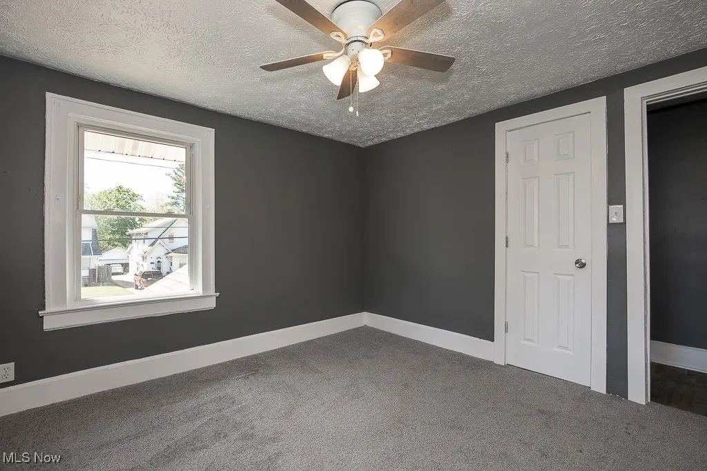 Bedroom with carpet, a textured ceiling, baseboards, and a ceiling fan
