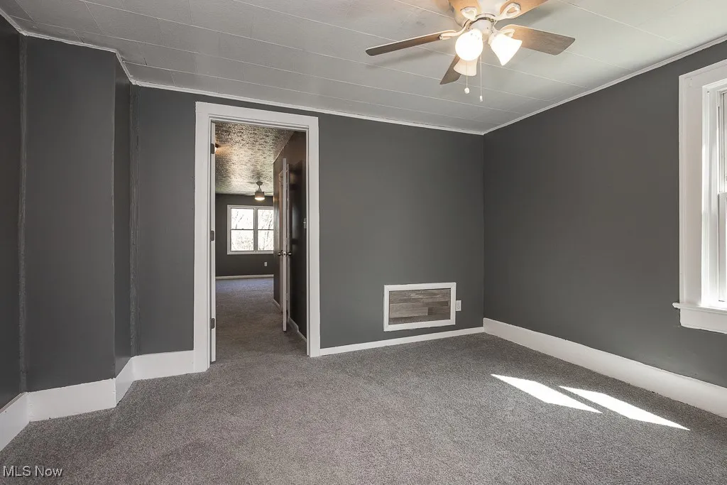Empty bedroom with carpet flooring, a ceiling fan, and baseboards