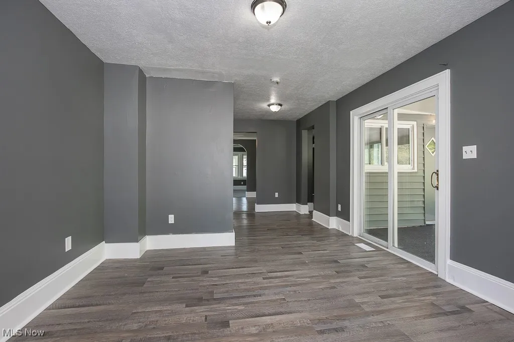 Family room featuring healthy amount of natural light, a textured ceiling, dark wood-type flooring, and baseboards