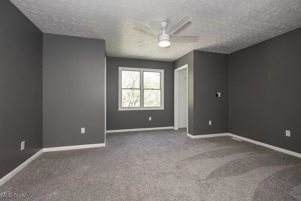 Carpeted bedroom featuring a ceiling fan, a textured ceiling, and baseboards