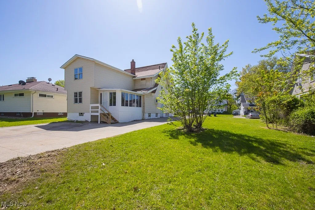 Back of house featuring a chimney and a lawn
