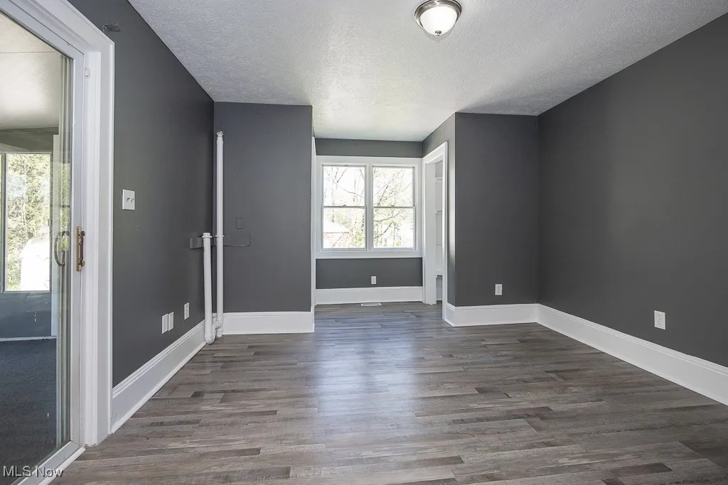Family room featuring a textured ceiling, dark wood-style flooring, and baseboards