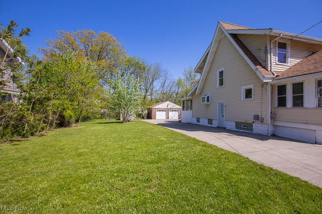 View of home's exterior with a garage, an outbuilding, a yard, and roof with shingles