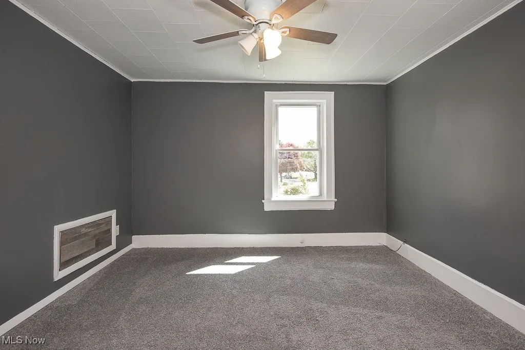 Carpeted bedroom with crown molding, ceiling fan, and baseboards