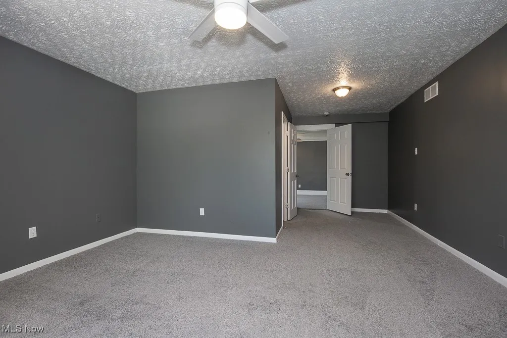 Carpeted bedroom featuring ceiling fan, a textured ceiling, and baseboards