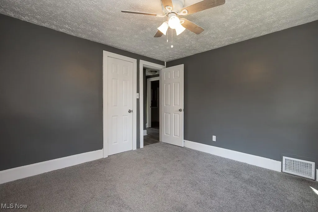 Unfurnished bedroom featuring carpet, a textured ceiling, baseboards, and ceiling fan