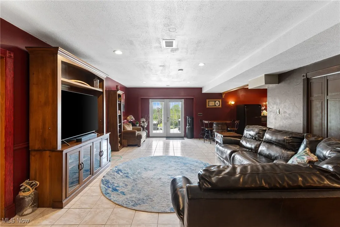 Living room featuring light tile patterned floors, a textured ceiling, french doors, and recessed lighting