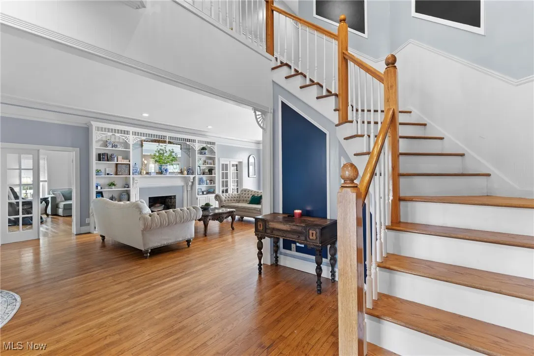 Stairs featuring crown molding, wood finished floors, a fireplace, and a towering ceiling
