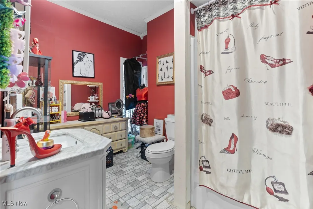 Bathroom featuring crown molding, toilet, vanity, shower / bathtub combination with curtain, and brick patterned flooring