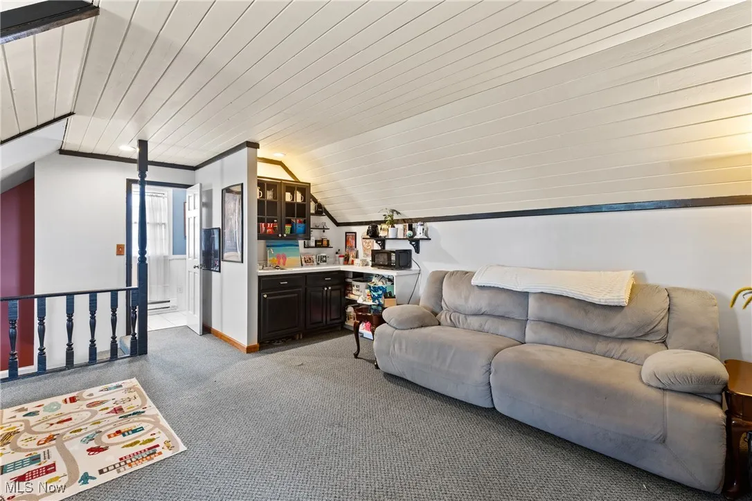 Living area featuring lofted ceiling, light colored carpet, and wood ceiling