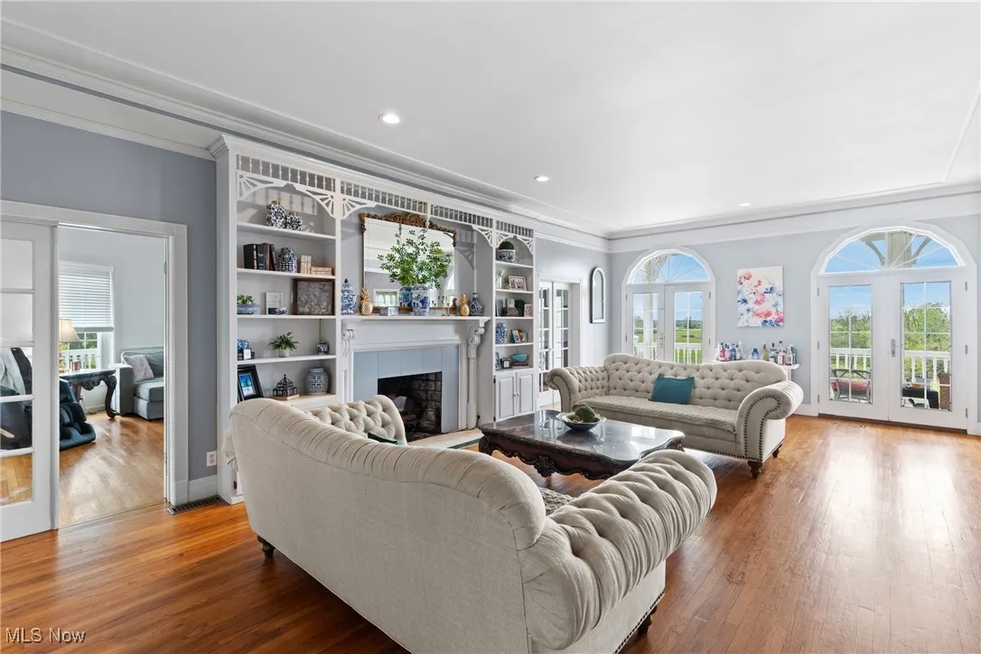 Living area featuring ornamental molding, a tiled fireplace, wood finished floors, recessed lighting, and built in shelves