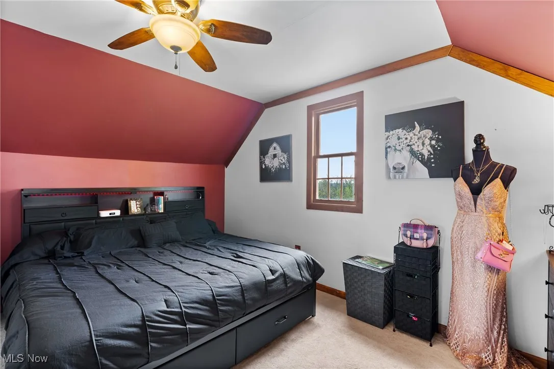 Bedroom featuring carpet floors, vaulted ceiling, a ceiling fan, and baseboards
