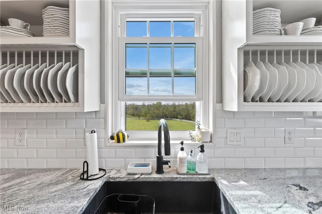 Kitchen featuring a sink, tasteful backsplash, and light stone counters