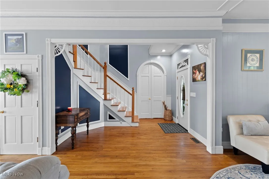 Entrance foyer featuring stairway, light wood-style flooring, crown molding, and baseboards