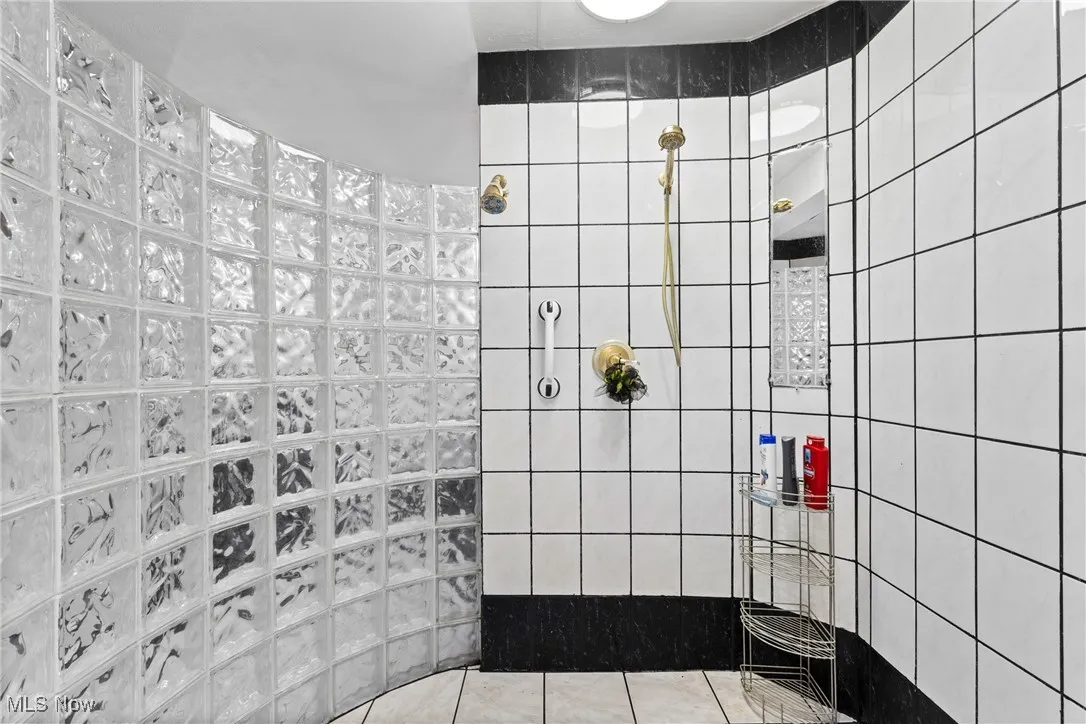 Bathroom with a walk in shower, tile patterned flooring, and tile walls