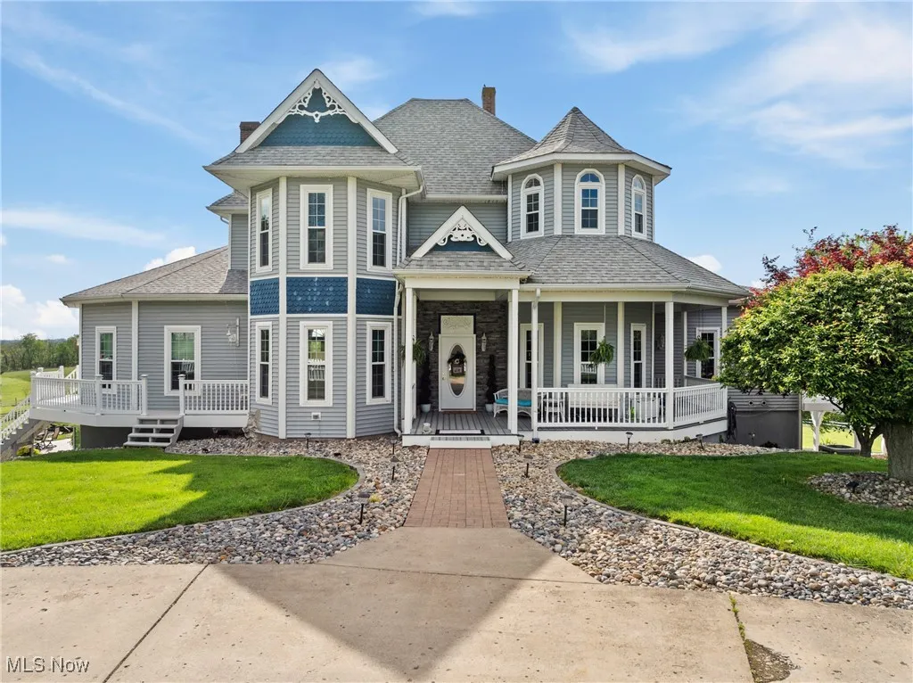 Victorian-style house with a porch, a front lawn, and roof with shingles