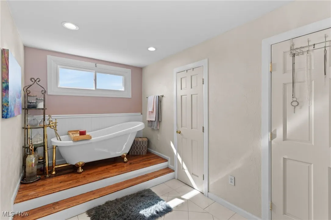 Bathroom featuring a freestanding tub, tile patterned flooring, wainscoting, recessed lighting, and baseboards