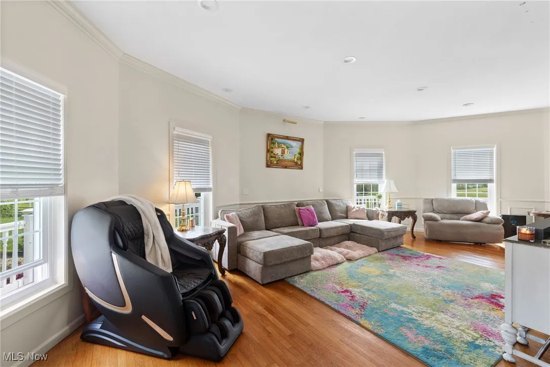 Living room featuring healthy amount of natural light, wood finished floors, and crown molding